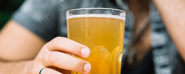 結婚指輪をしている男性がビールを飲んでいる